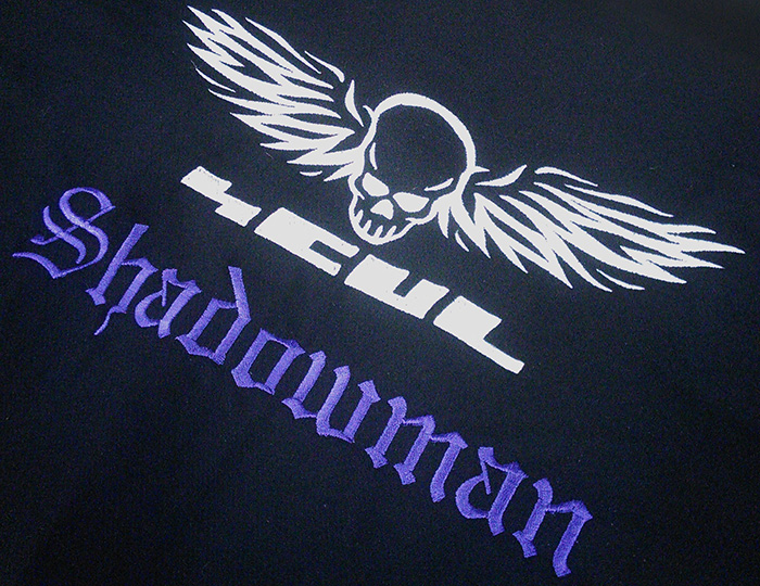 an embroidered peice of black wool with the SCUL logo and the word 'Shadowman' in old English letters in purple beneath it